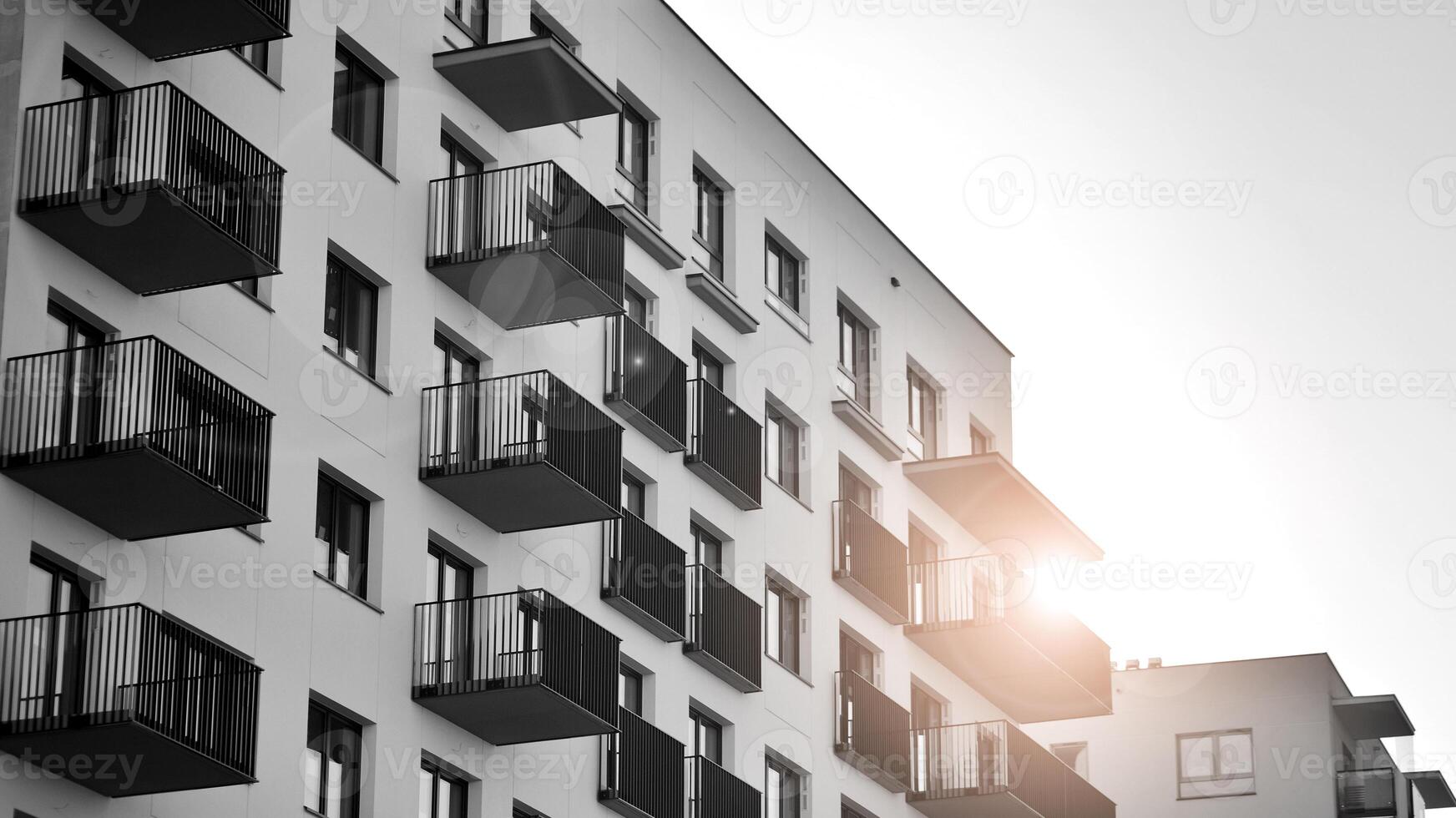 Fragment of the building's facade with windows and balconies. Modern apartment buildings on a sunny day. Facade of a modern residential building. Black and white. photo