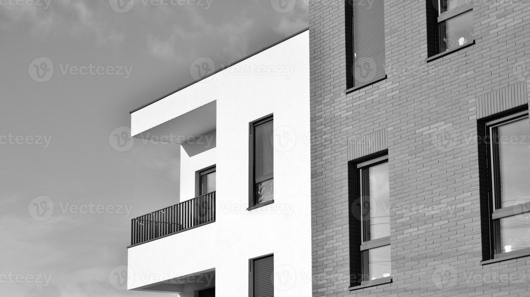 Fragment of the building's facade with windows and balconies. Modern apartment buildings on a sunny day. Facade of a modern residential building. Black and white. photo
