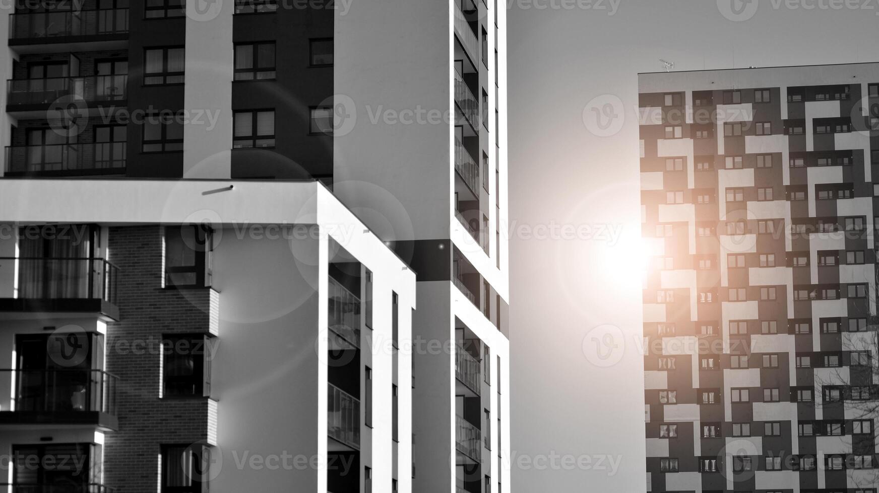 Fragment of the building's facade with windows and balconies. Modern apartment buildings on a sunny day. Facade of a modern residential building. Black and white. photo