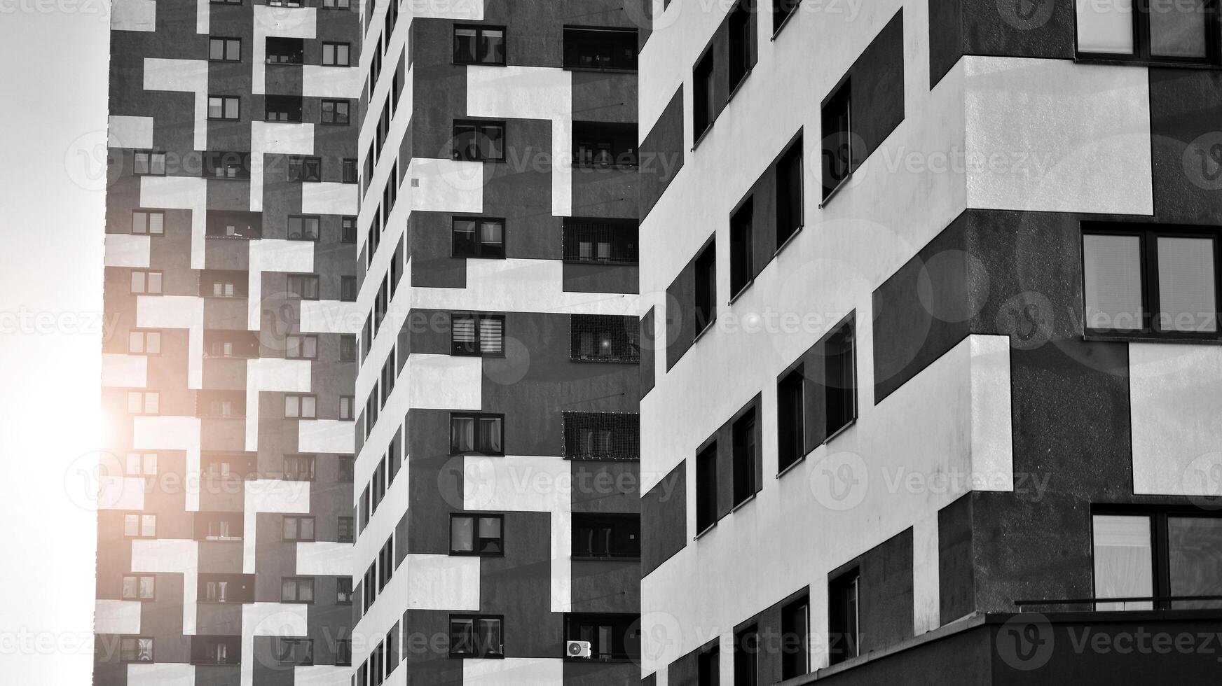 Fragment of the building's facade with windows and balconies. Modern apartment buildings on a sunny day. Facade of a modern residential building. Black and white. photo