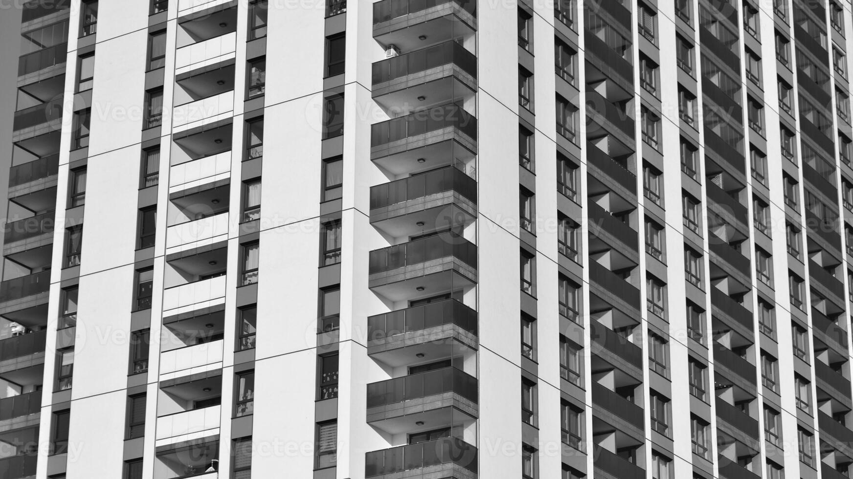 Fragment of the building's facade with windows and balconies. Modern apartment buildings on a sunny day. Facade of a modern residential building. Black and white. photo