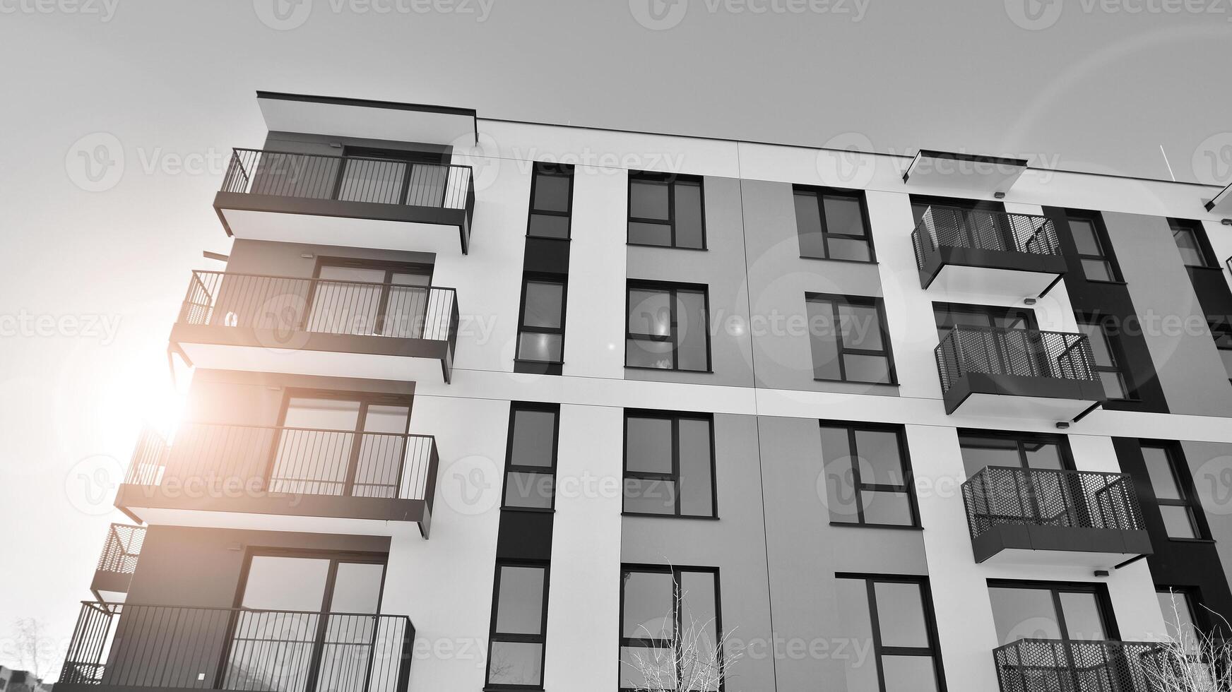 Fragment of the building's facade with windows and balconies. Modern apartment buildings on a sunny day. Facade of a modern residential building. Black and white. photo