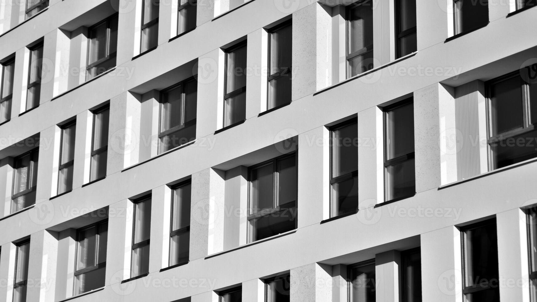 Fragment of the building's facade with windows and balconies. Modern apartment buildings on a sunny day. Facade of a modern residential building. Black and white. photo