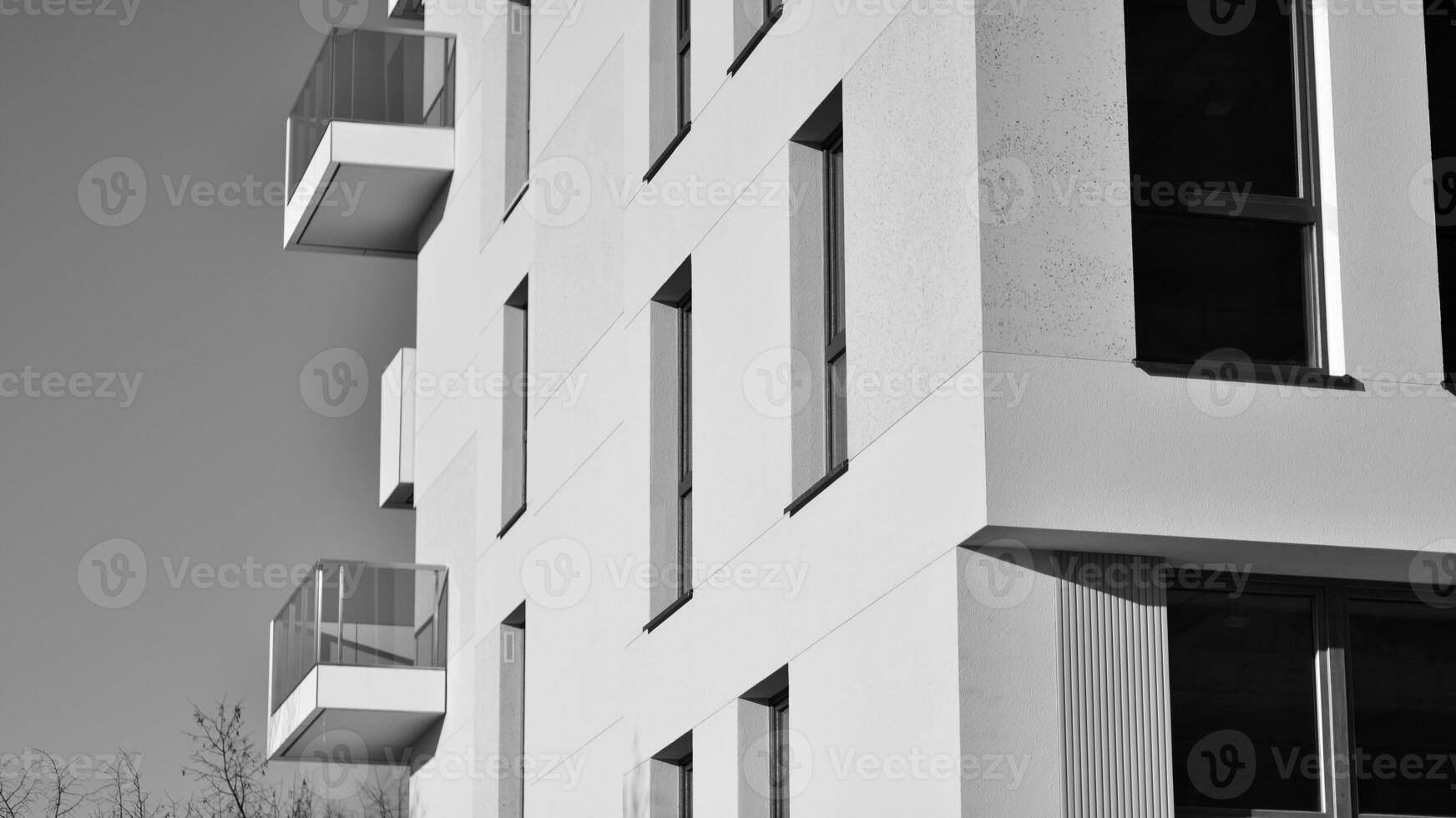 Fragment of the building's facade with windows and balconies. Modern apartment buildings on a sunny day. Facade of a modern residential building. Black and white. photo