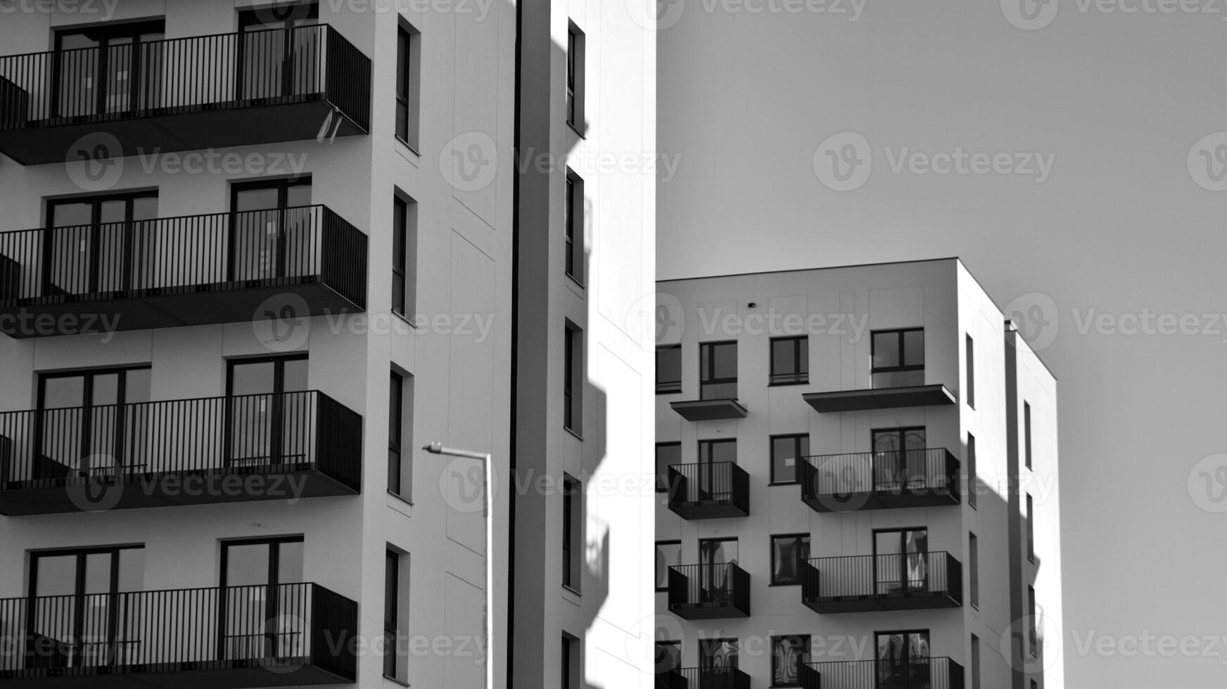 Fragment of the building's facade with windows and balconies. Modern apartment buildings on a sunny day. Facade of a modern residential building. Black and white. photo