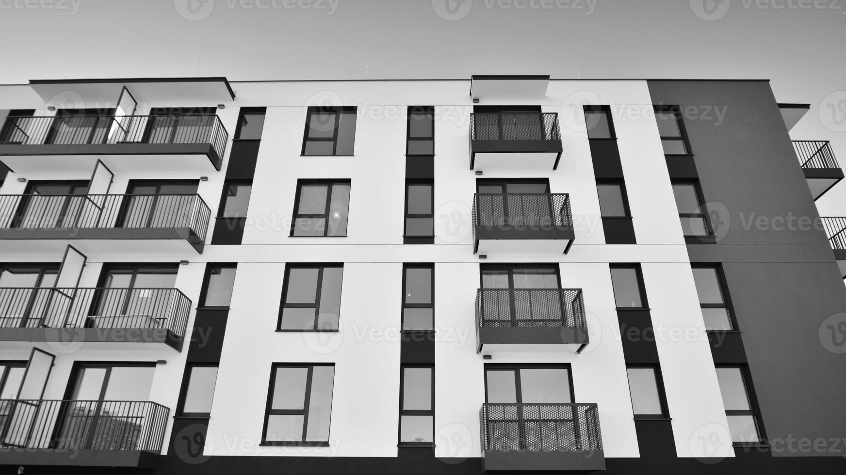 Fragment of the building's facade with windows and balconies. Modern apartment buildings on a sunny day. Facade of a modern residential building. Black and white. photo