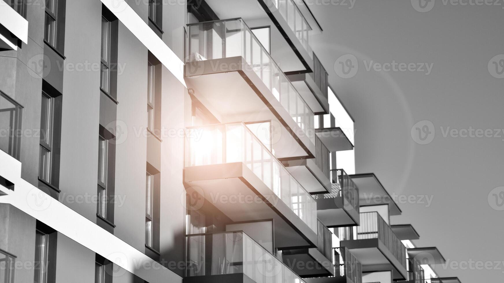 Fragment of the building's facade with windows and balconies. Modern apartment buildings on a sunny day. Facade of a modern residential building. Black and white. photo