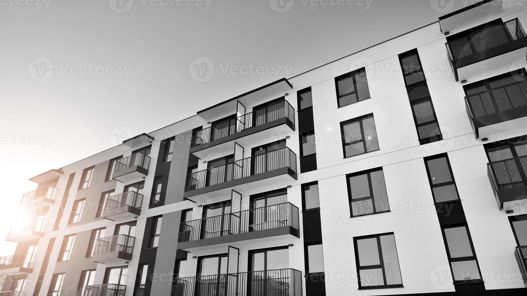 Fragment of the building's facade with windows and balconies. Modern apartment buildings on a sunny day. Facade of a modern residential building. Black and white. photo
