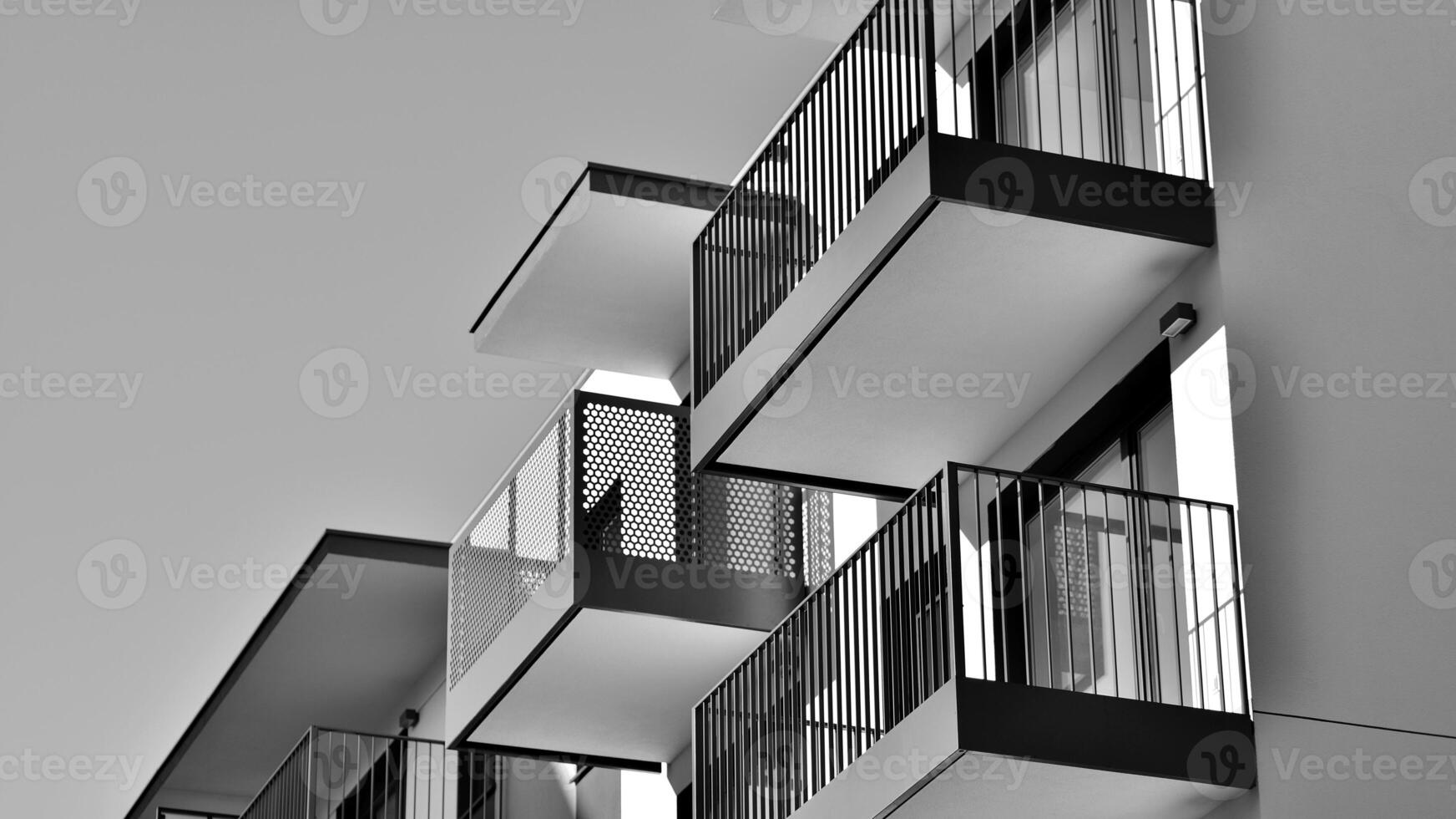 Fragment of the building's facade with windows and balconies. Modern apartment buildings on a sunny day. Facade of a modern residential building. Black and white. photo