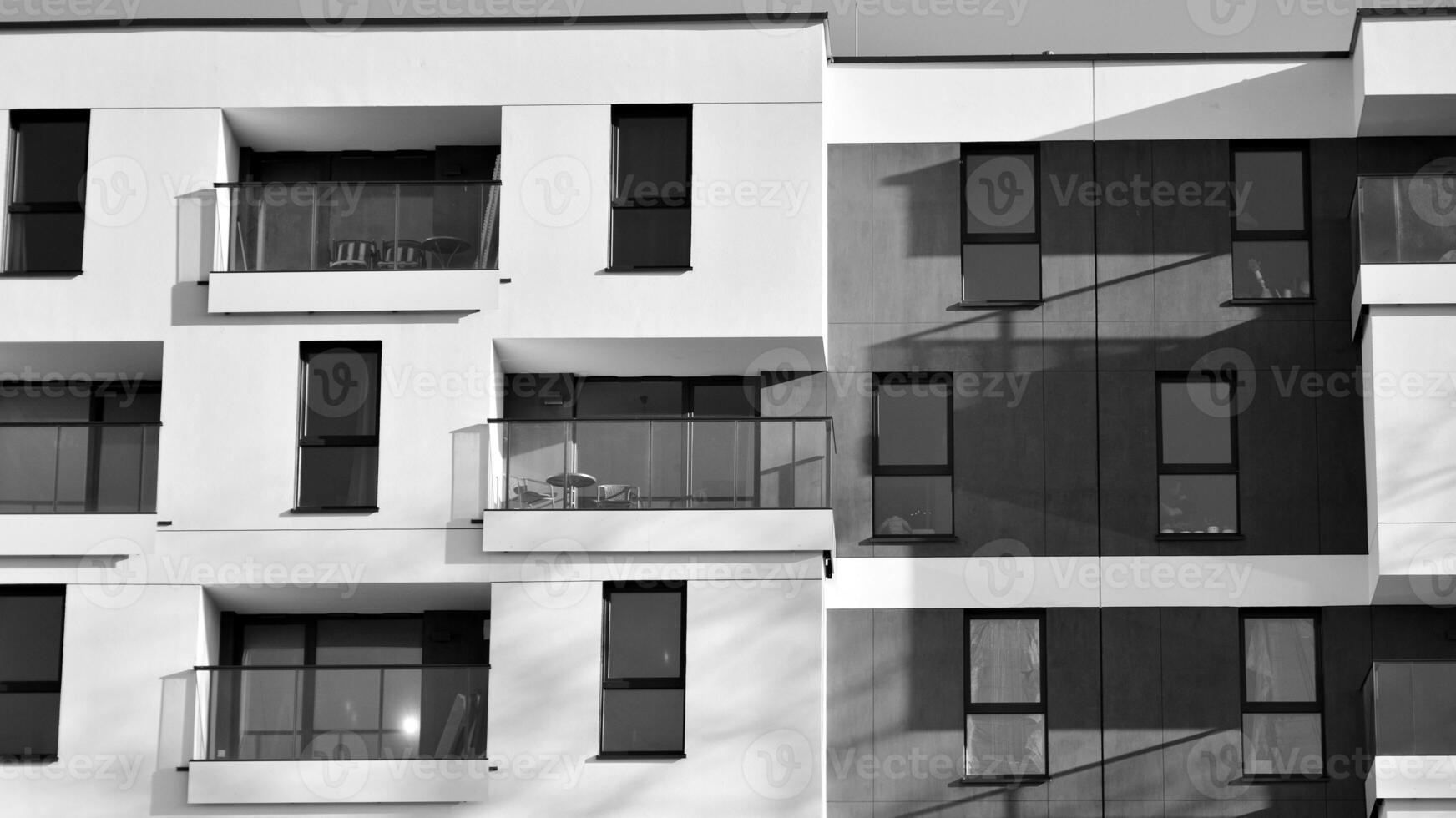 Fragment of a facade of a building with windows and balconies. Modern apartment buildings on a sunny day. Facade of a modern apartment building. Black and white. photo