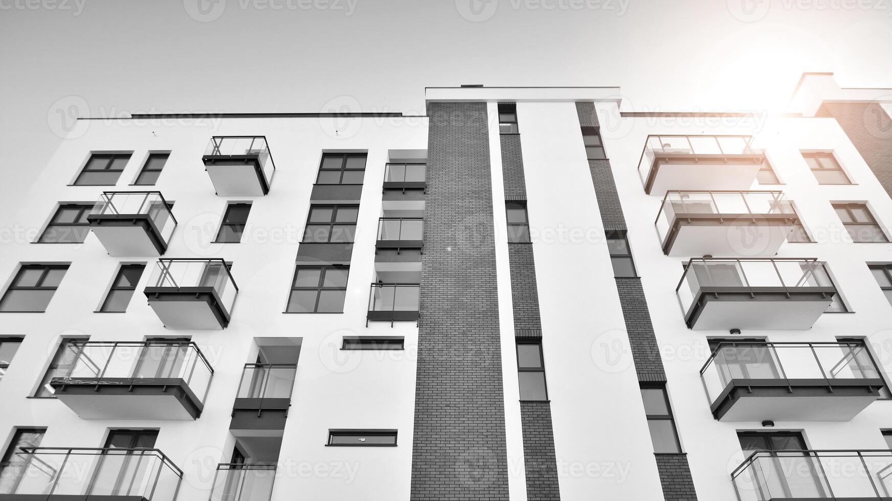 Fragment of a facade of a building with windows and balconies. Modern apartment buildings on a sunny day. Facade of a modern apartment building. Black and white. photo