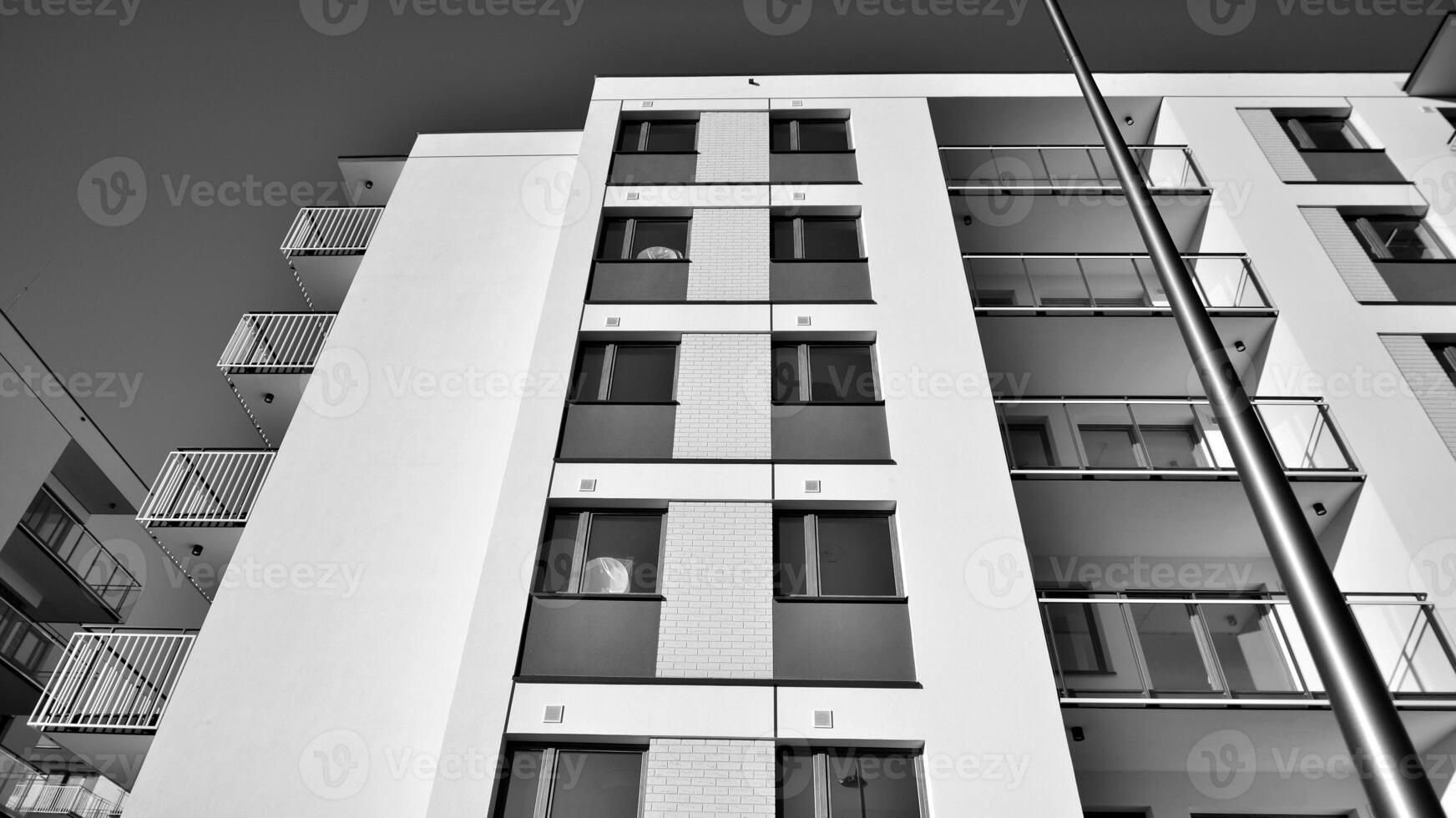 Fragment of a facade of a building with windows and balconies. Modern apartment buildings on a sunny day. Facade of a modern apartment building. Black and white. photo