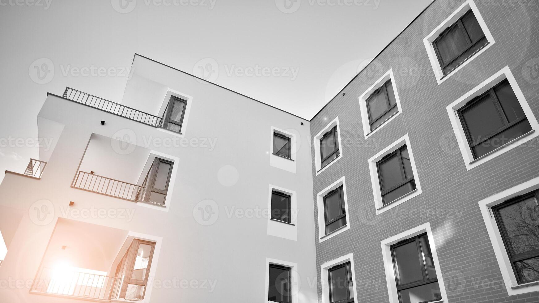 Fragment of a facade of a building with windows and balconies. Modern apartment buildings on a sunny day. Facade of a modern apartment building. Black and white. photo