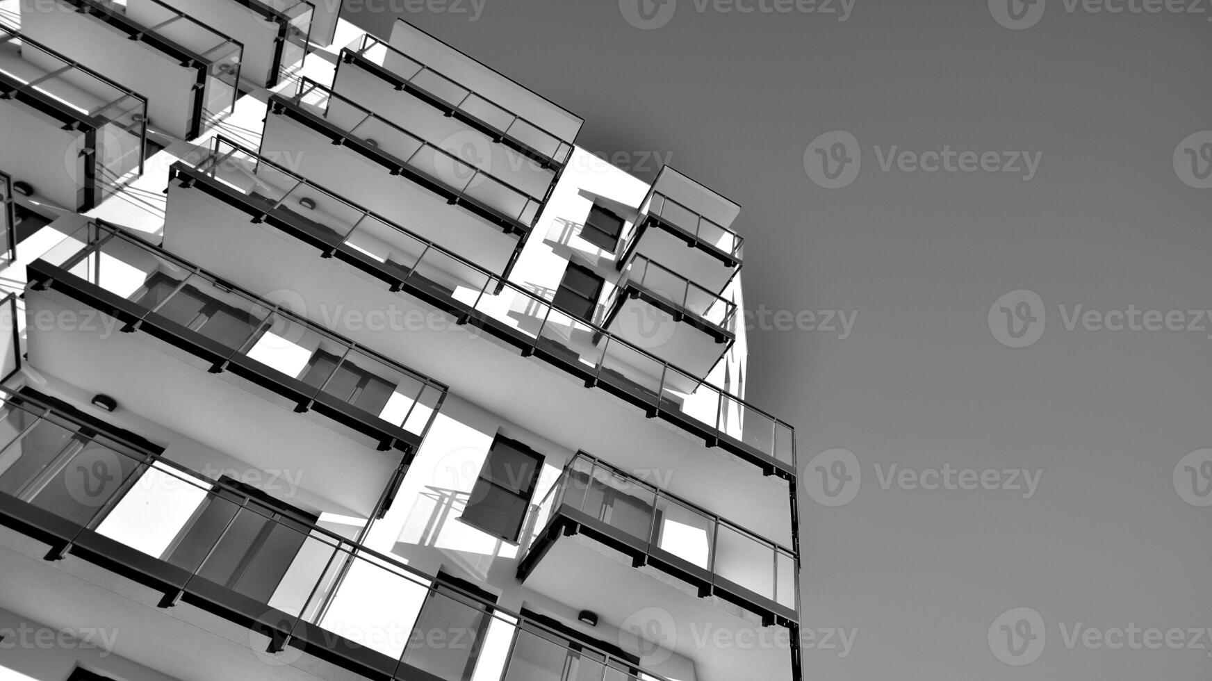 Fragment of a facade of a building with windows and balconies. Modern apartment buildings on a sunny day. Facade of a modern apartment building. Black and white. photo
