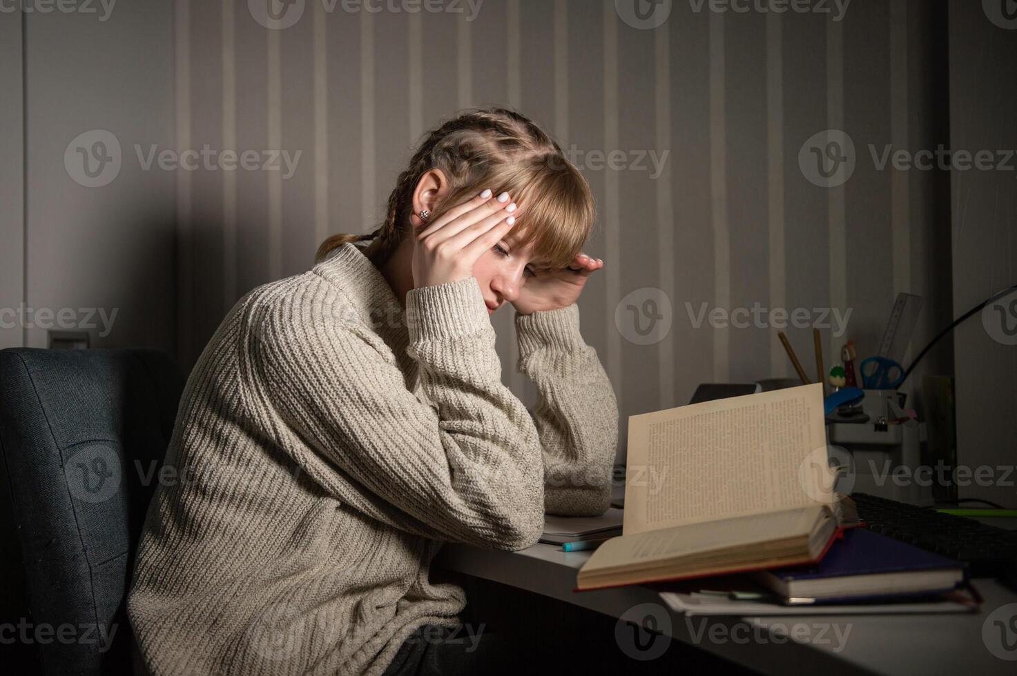 An overworked student falls asleep reading a book in the dark. Overtime processing. Study after work photo