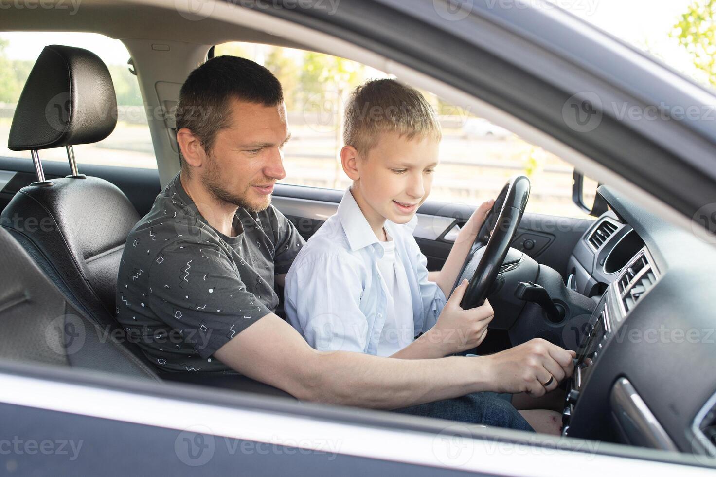 Dad shows his son how to drive a car. The child is driving with dad photo