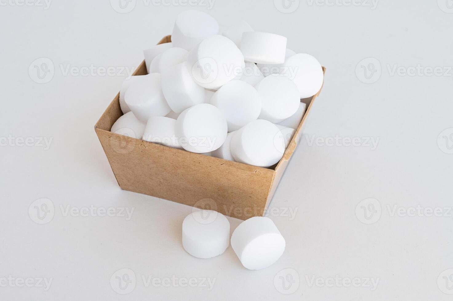 White tablets of pressed salt for the dishwasher close-up. Place for text photo