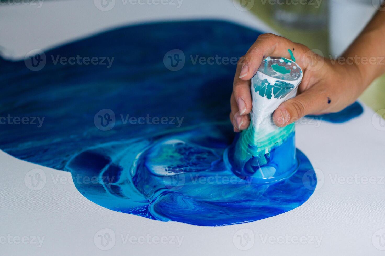 Artistic Hand Mixing Blue Paints on Canvas photo