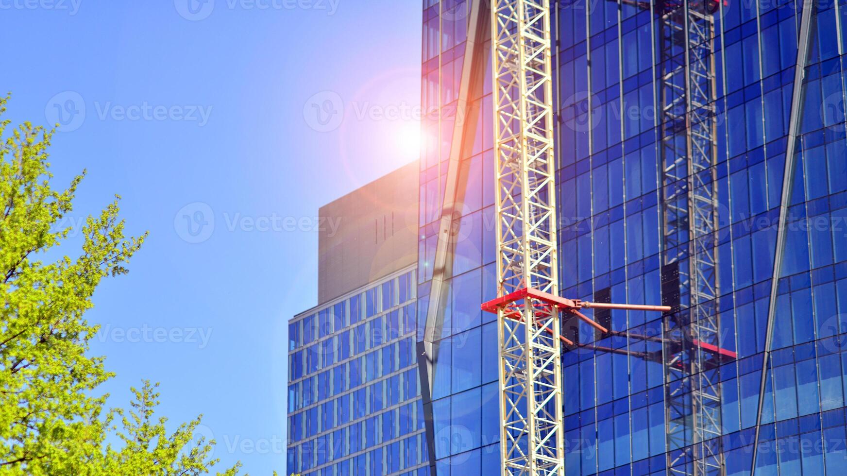 High rise building under construction. Installation of glass facade panels on a reinforced concrete structure. photo
