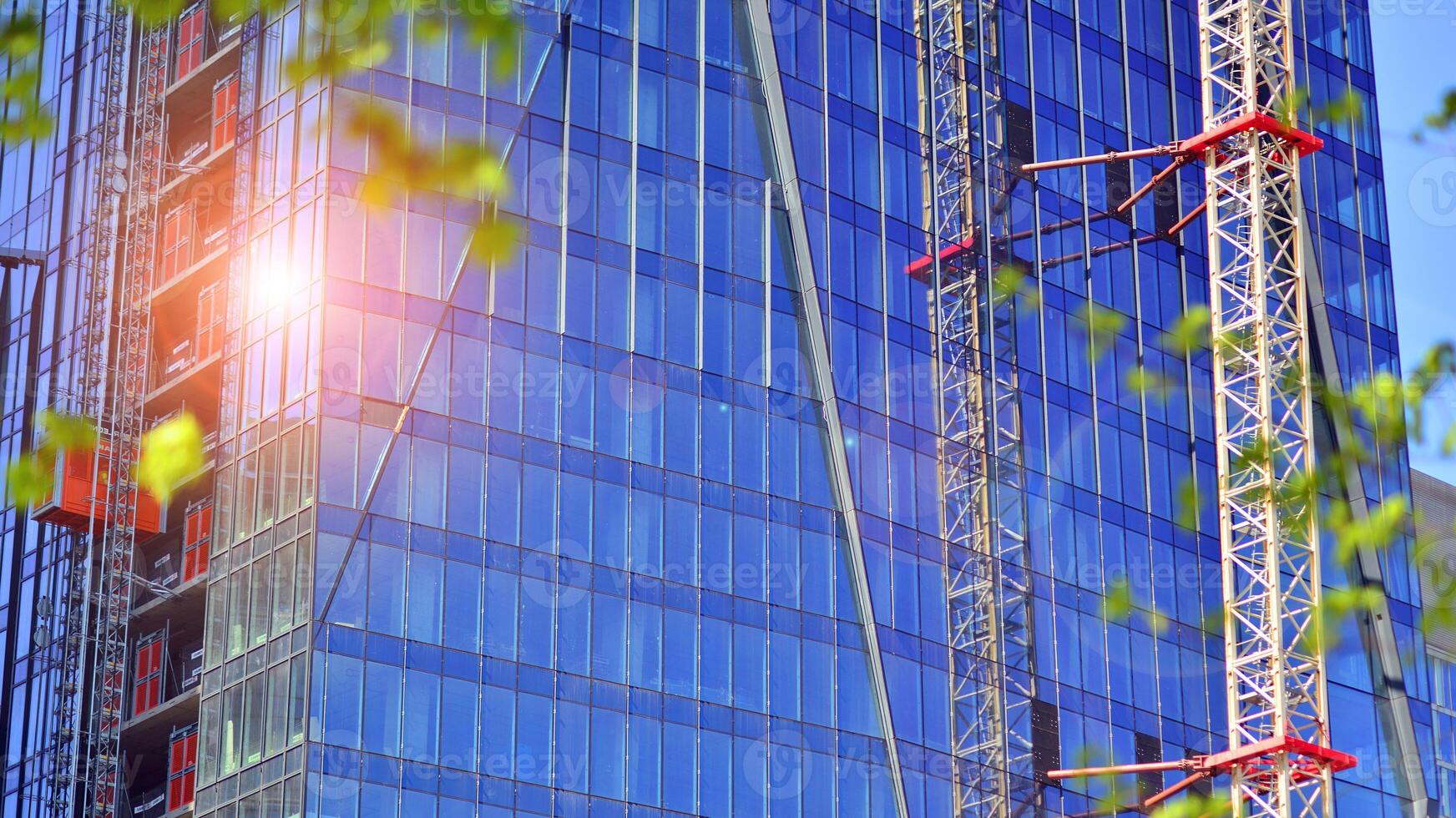 High rise building under construction. Installation of glass facade panels on a reinforced concrete structure. photo
