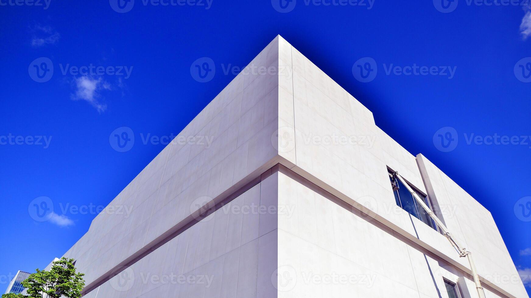 Modern white concrete building walls against blue sky. Eco architecture. Green trees and concrete office building. The harmony of nature and modernity. photo