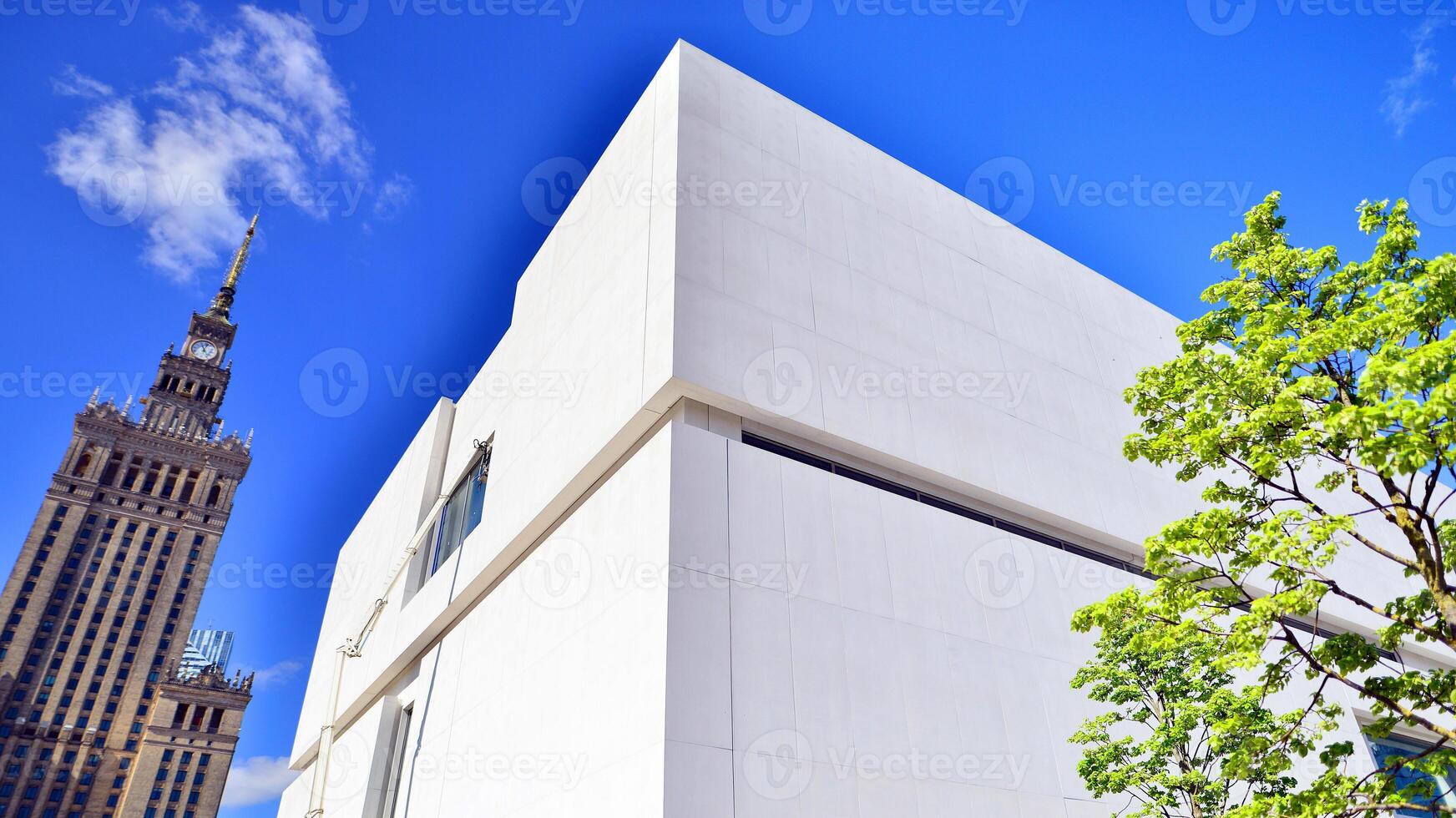 Modern white concrete building walls against blue sky. Eco architecture. Green trees and concrete office building. The harmony of nature and modernity. photo