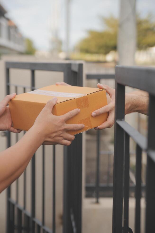 Asian delivery express courier young man use giving boxes to woman customer he wearing protective face mask at front home photo