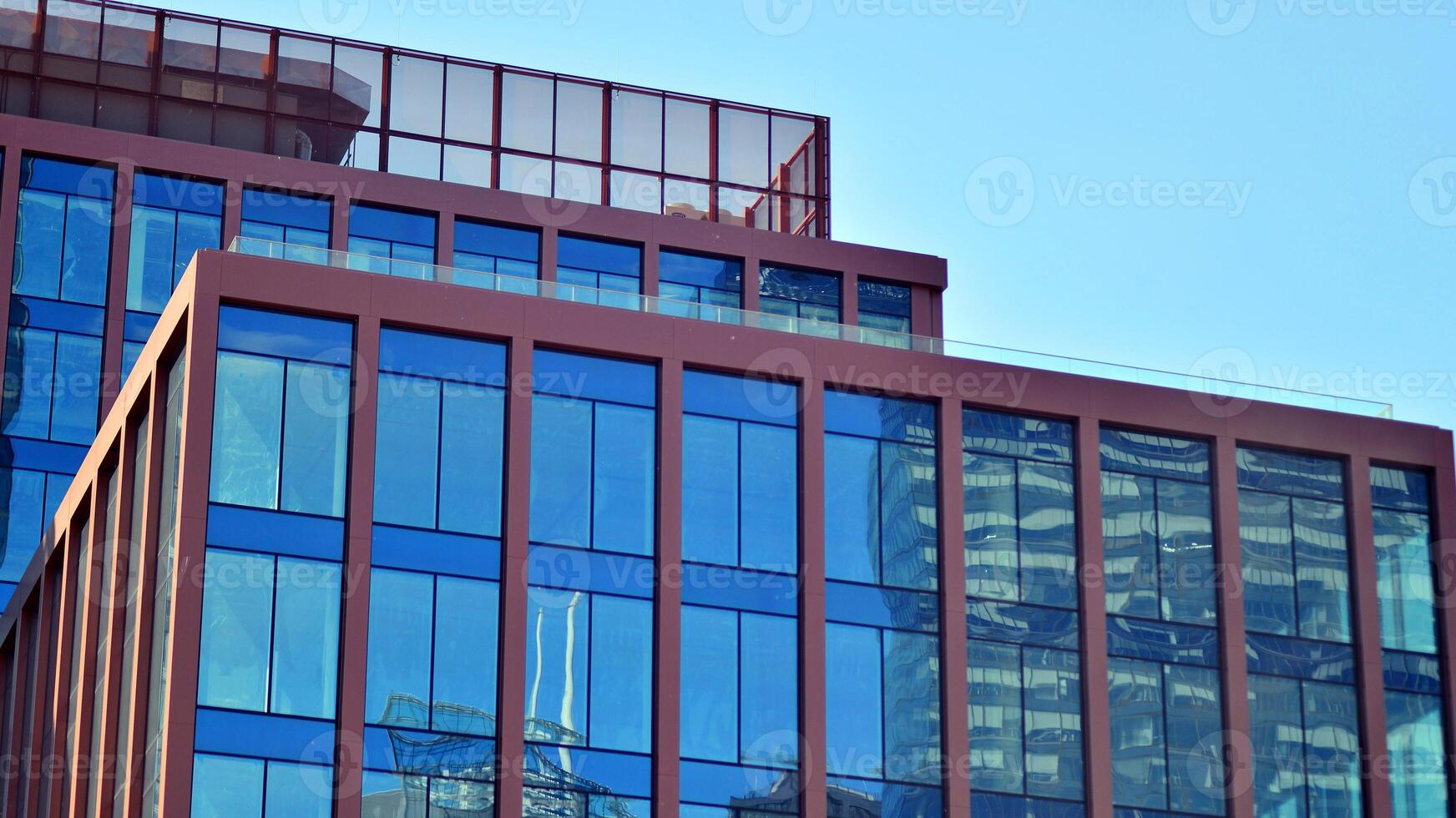 Glass building with transparent facade of the building and blue sky. Structural glass wall reflecting blue sky. Abstract modern architecture fragment. Contemporary architectural background. photo
