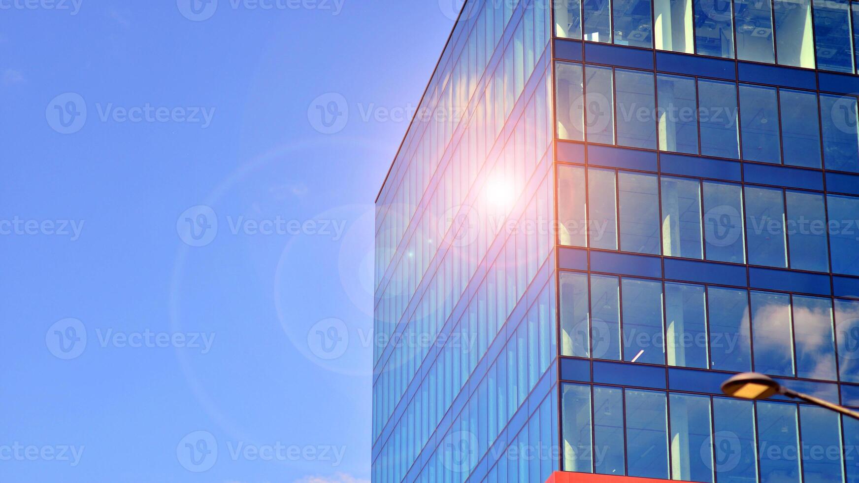 Glass building with transparent facade of the building and blue sky. Structural glass wall reflecting blue sky. Abstract modern architecture fragment. Contemporary architectural background. photo
