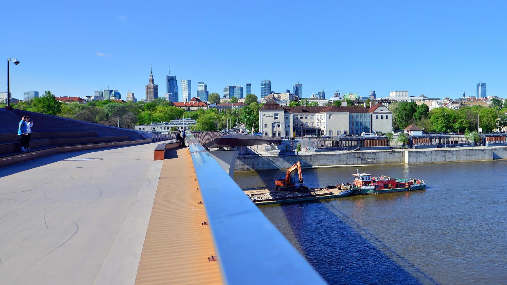 Warsaw, Poland. 11 April 2024. Bridge over the Vistula River intended only for pedestrians and cyclists. In the background, a panorama of the city with skyscrapers. photo