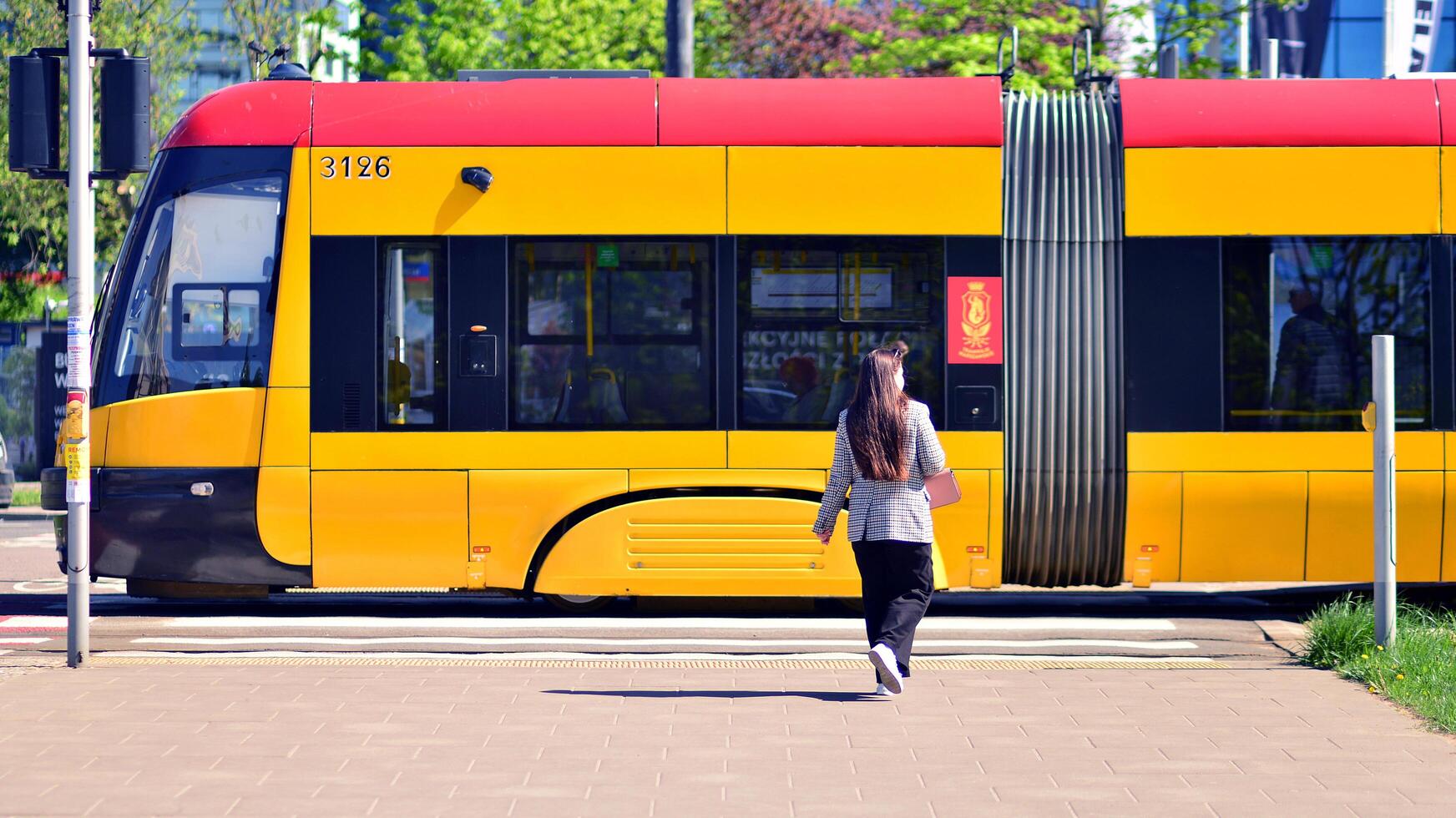 Warsaw, Poland. 11 April 2024. Tram stop in the center. Woman waiting city public tram. photo
