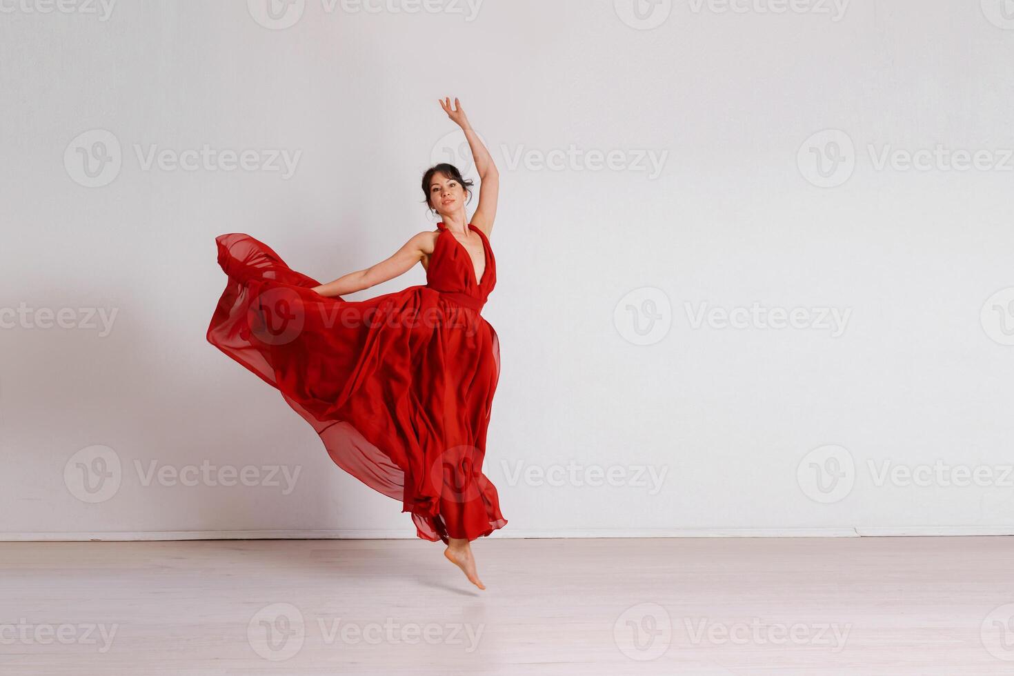 Dancer in a red flying dress. Woman ballerina dancing on a white studio background photo