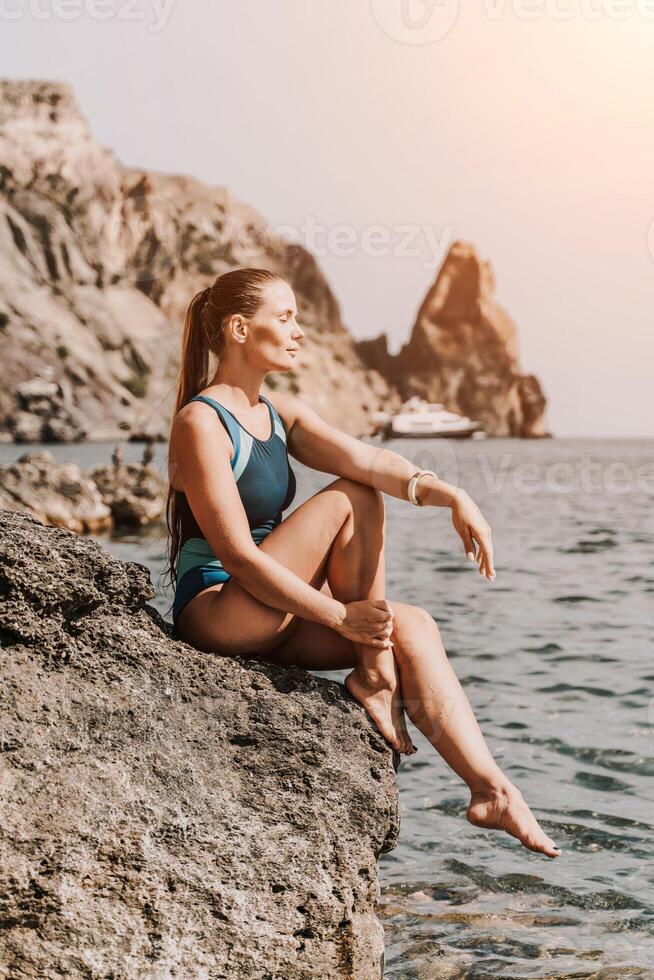 Woman travel summer sea. A happy tourist in a blue bikini enjoying the scenic view of the sea and volcanic mountains while taking pictures to capture the memories of her travel adventure. photo