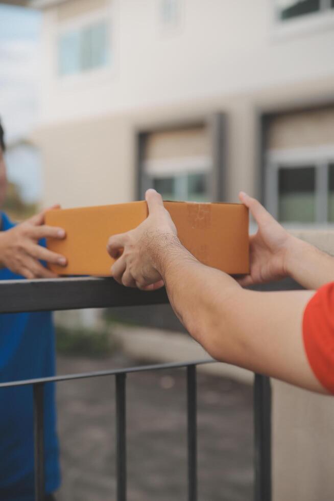 Asian delivery express courier young man use giving boxes to woman customer he wearing protective face mask at front home photo
