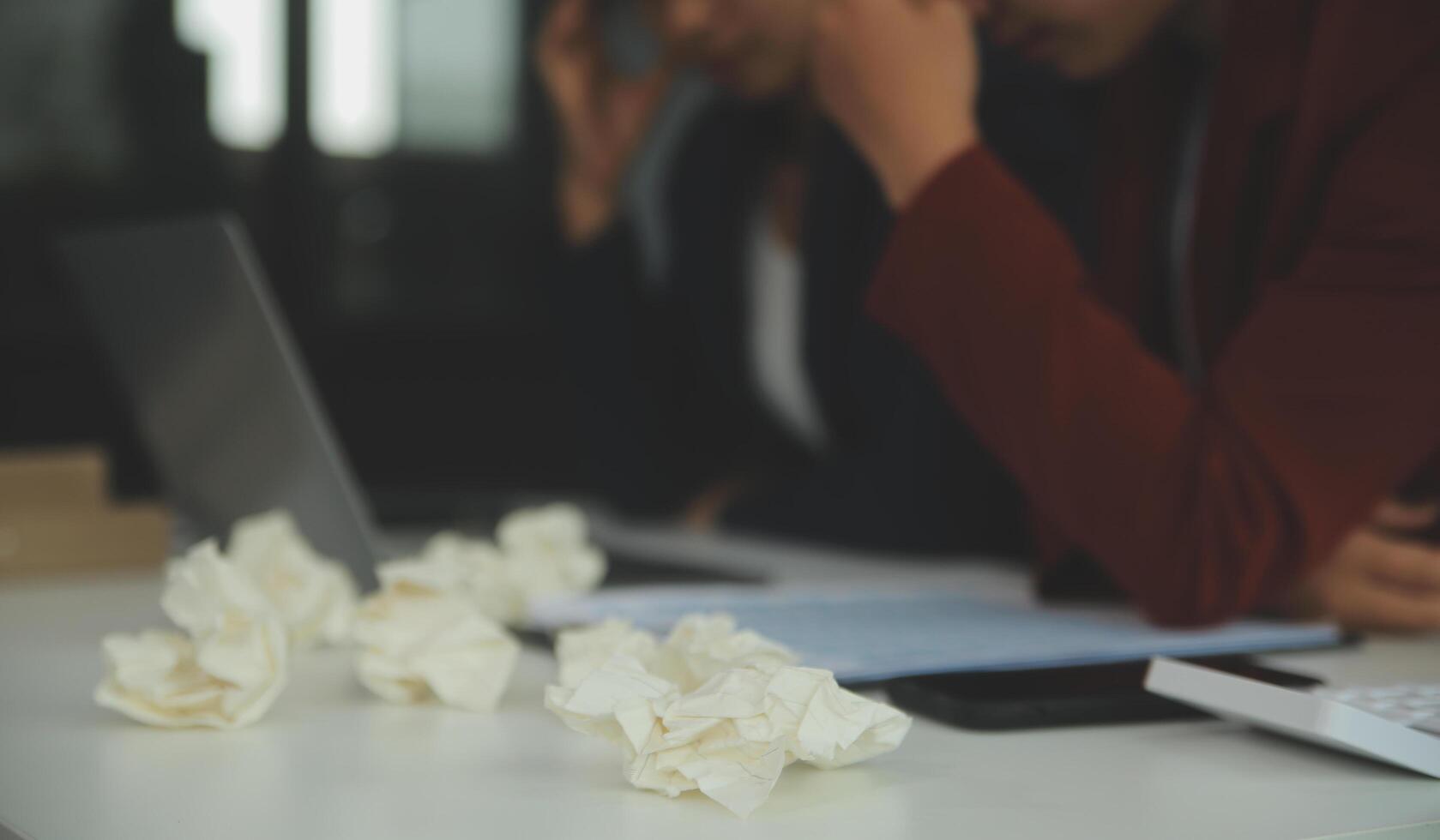Stressed annoyed office employee manager having headache migraine at business meeting with his colleagues about business problem they have to solve. Stress at work or migraine concept. photo
