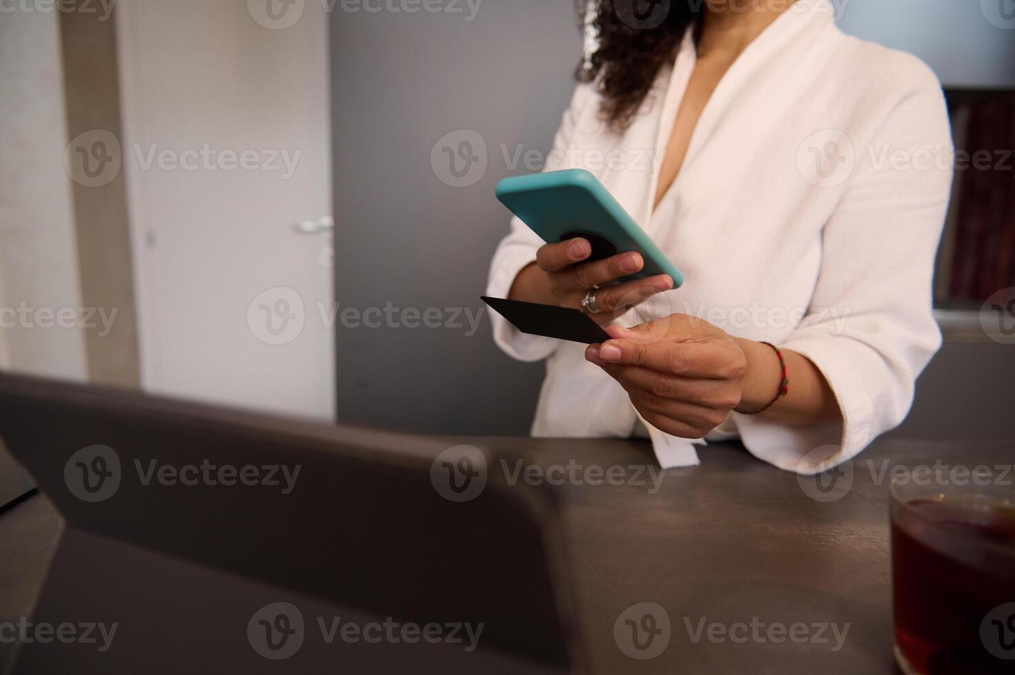 Close-up view of a woman holding blank black credit card, using mobile phone, transferring money via internet banking, making payment, using mobile app. Copy advertising space photo