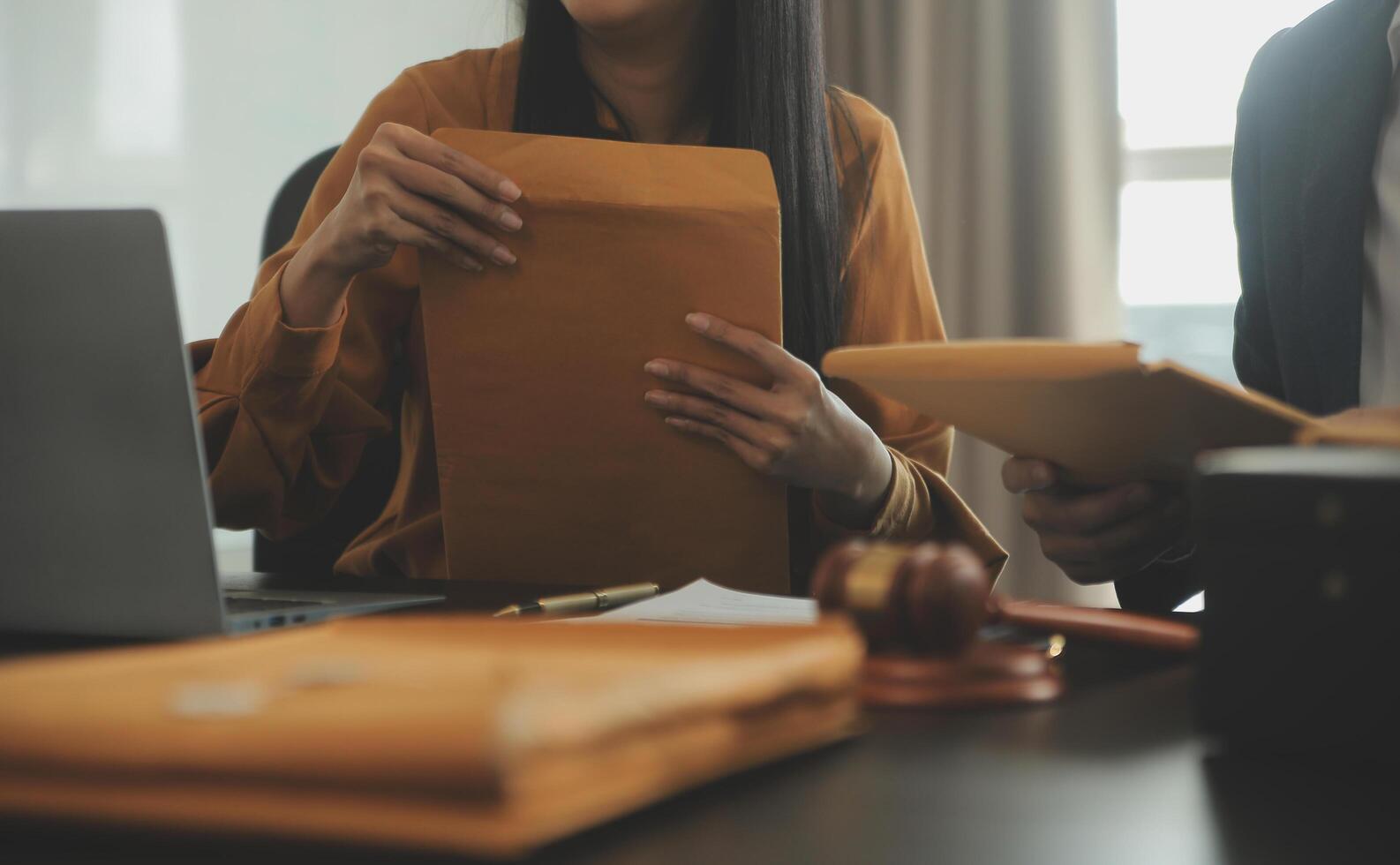 Justice and Law concept. Legal counsel presents to the client a signed contract with gavel and legal law or legal having team meeting at law firm in background photo