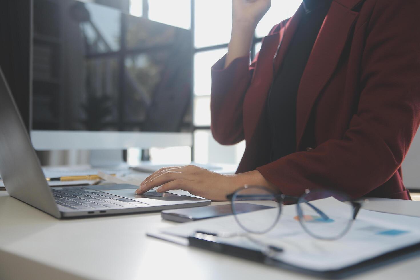 Cropped image of professional businesswoman working at her office via laptop, young female manager using portable computer device while sitting at modern loft, flare light, work process concept photo