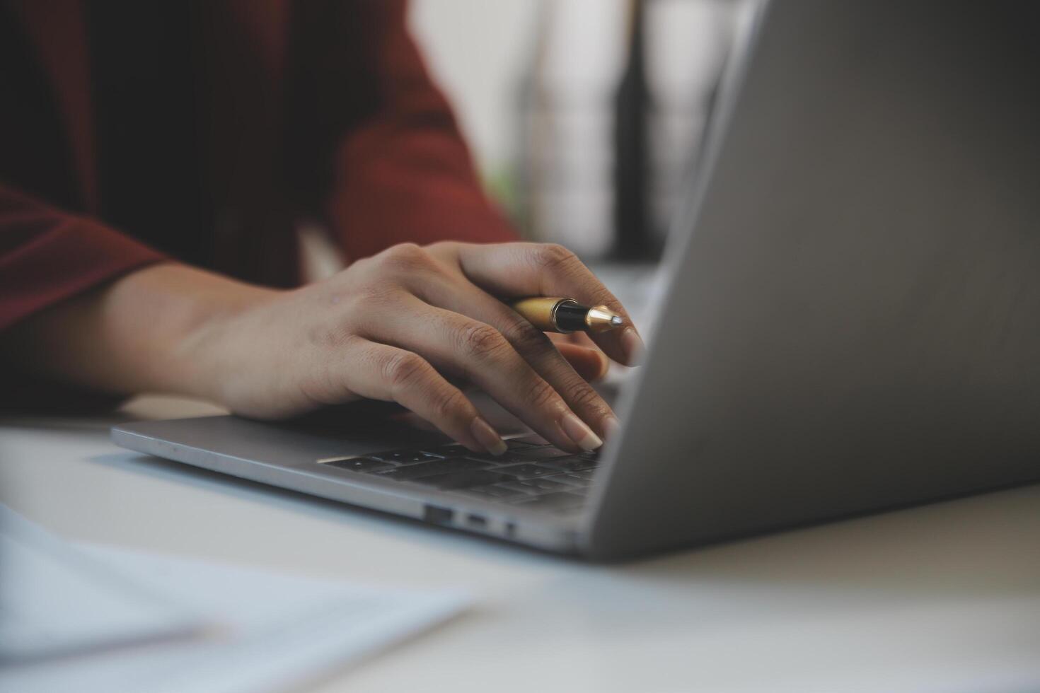 Cropped image of professional businesswoman working at her office via laptop, young female manager using portable computer device while sitting at modern loft, flare light, work process concept photo