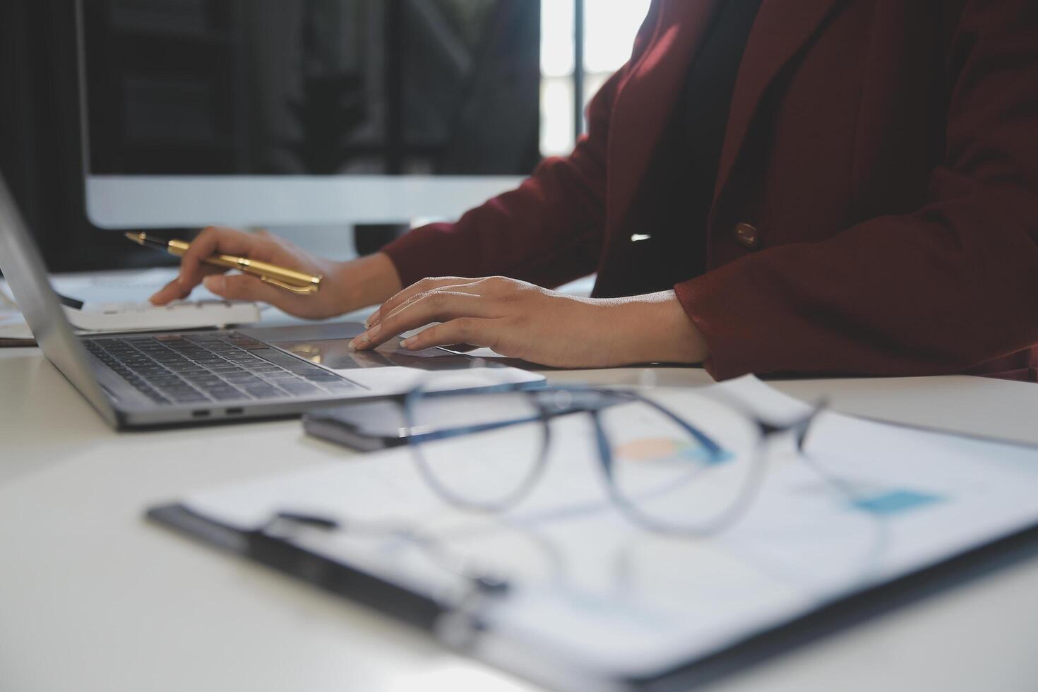 Cropped image of professional businesswoman working at her office via laptop, young female manager using portable computer device while sitting at modern loft, flare light, work process concept photo