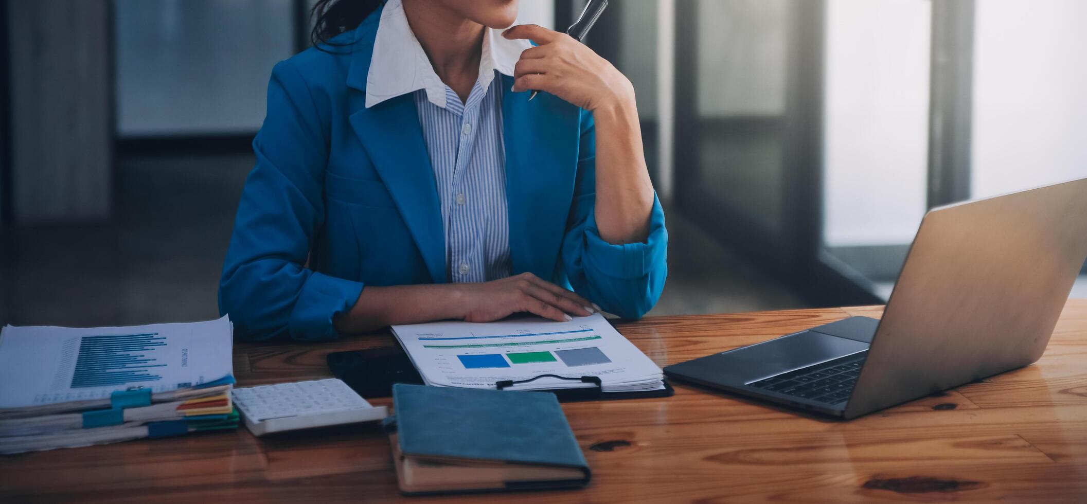 Asian Business woman using calculator and laptop for doing math finance on an office desk, tax, report, accounting, statistics, and analytical research concept photo