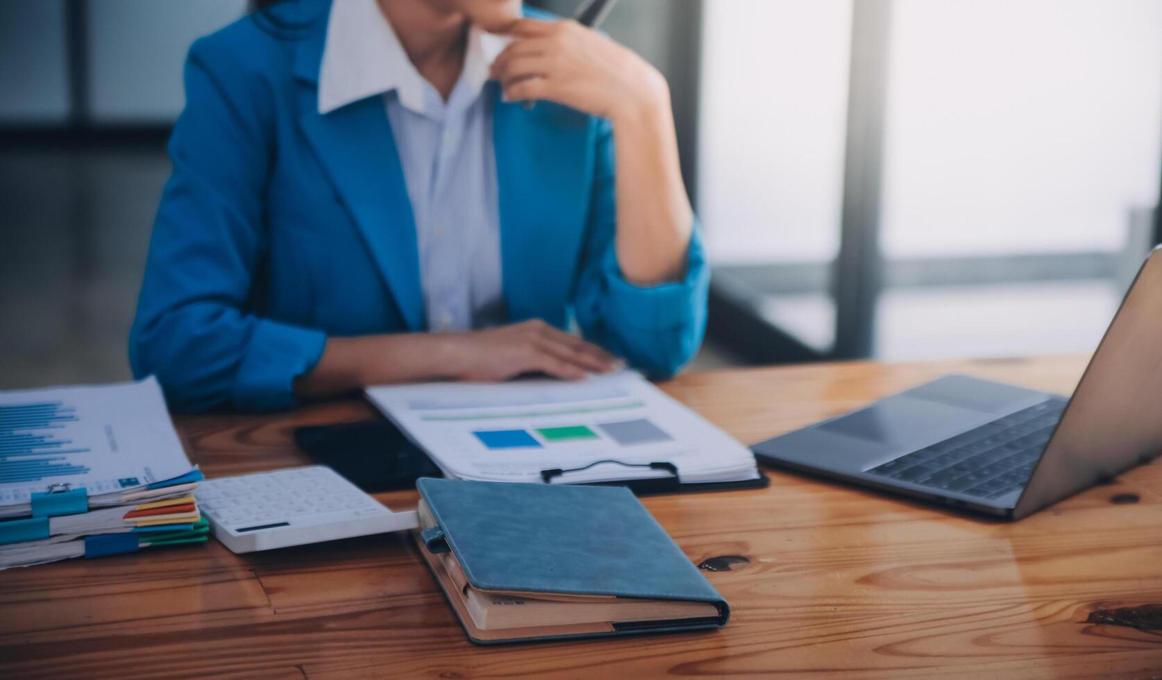 Asian Business woman using calculator and laptop for doing math finance on an office desk, tax, report, accounting, statistics, and analytical research concept photo