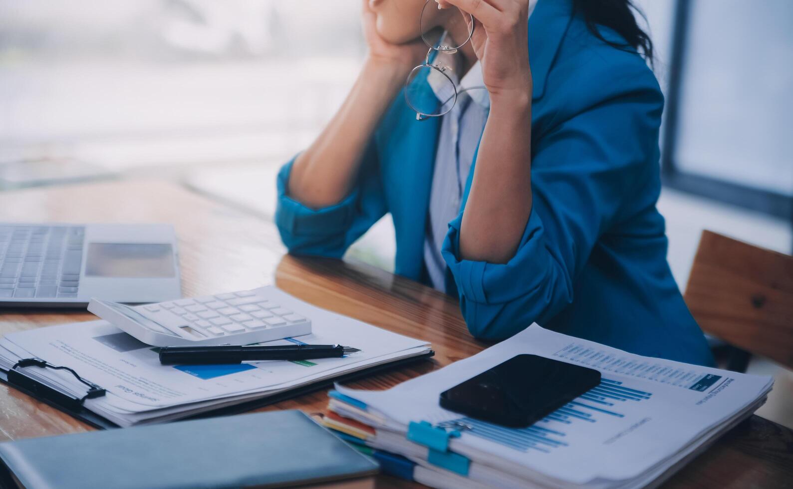 Asian Business woman using calculator and laptop for doing math finance on an office desk, tax, report, accounting, statistics, and analytical research concept photo