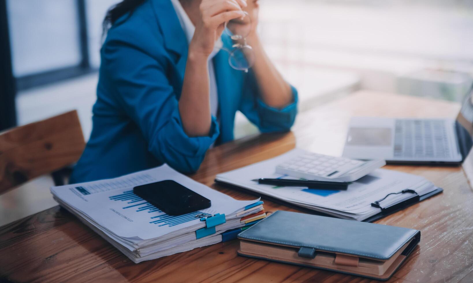 Asian Business woman using calculator and laptop for doing math finance on an office desk, tax, report, accounting, statistics, and analytical research concept photo