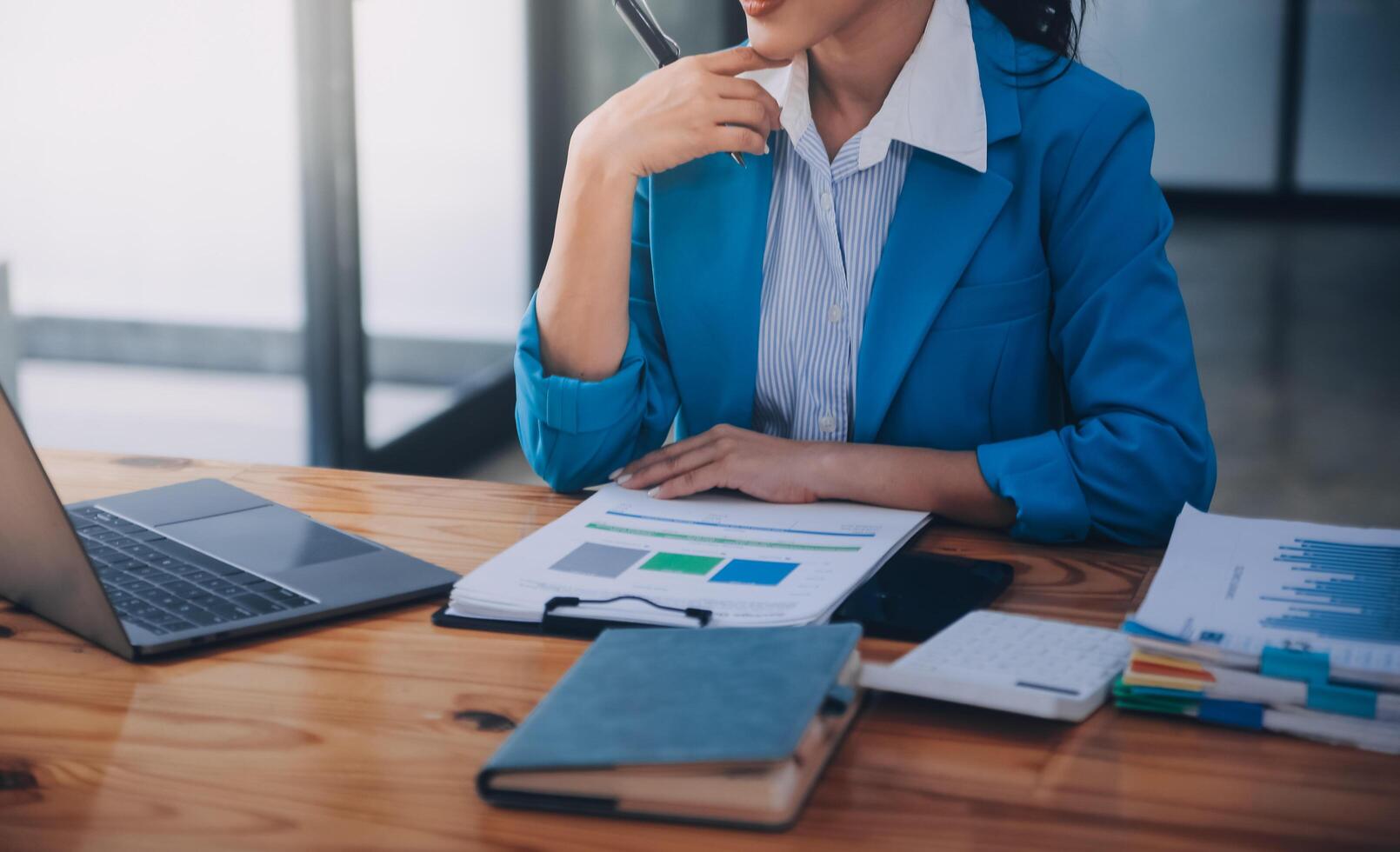 Asian Business woman using calculator and laptop for doing math finance on an office desk, tax, report, accounting, statistics, and analytical research concept photo