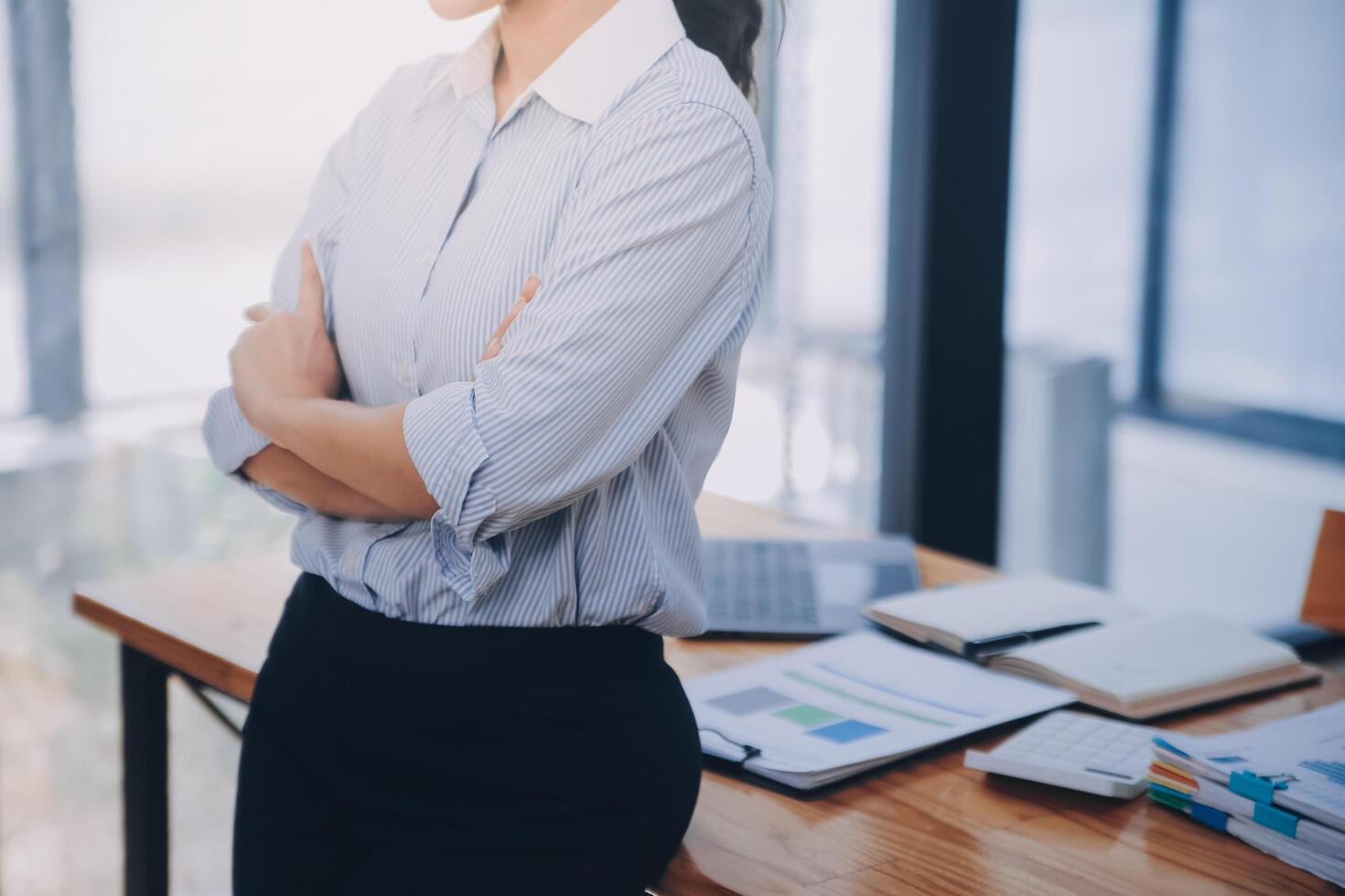 Asian Business woman using calculator and laptop for doing math finance on an office desk, tax, report, accounting, statistics, and analytical research concept photo