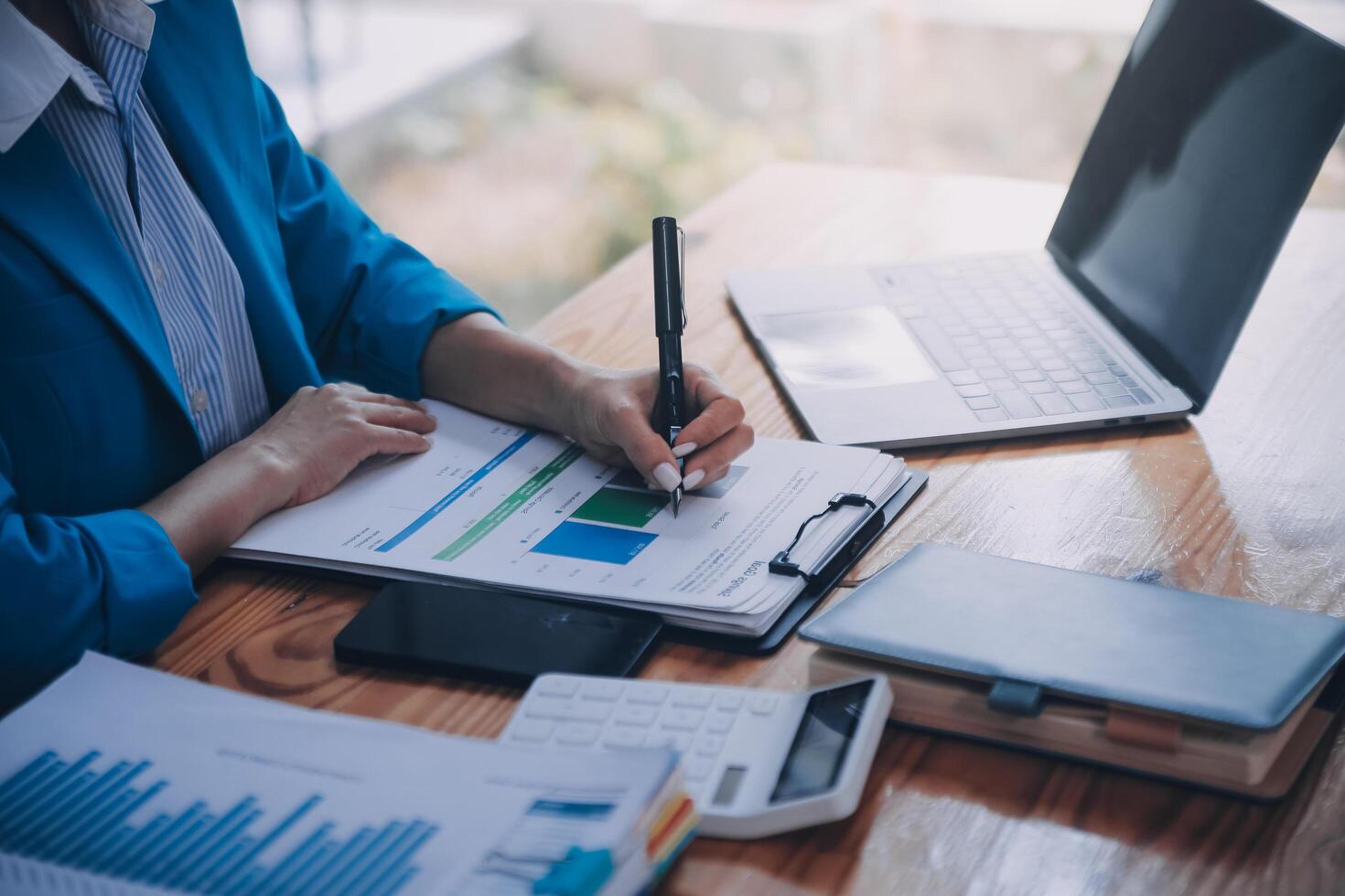 Asian Business woman using calculator and laptop for doing math finance on an office desk, tax, report, accounting, statistics, and analytical research concept photo