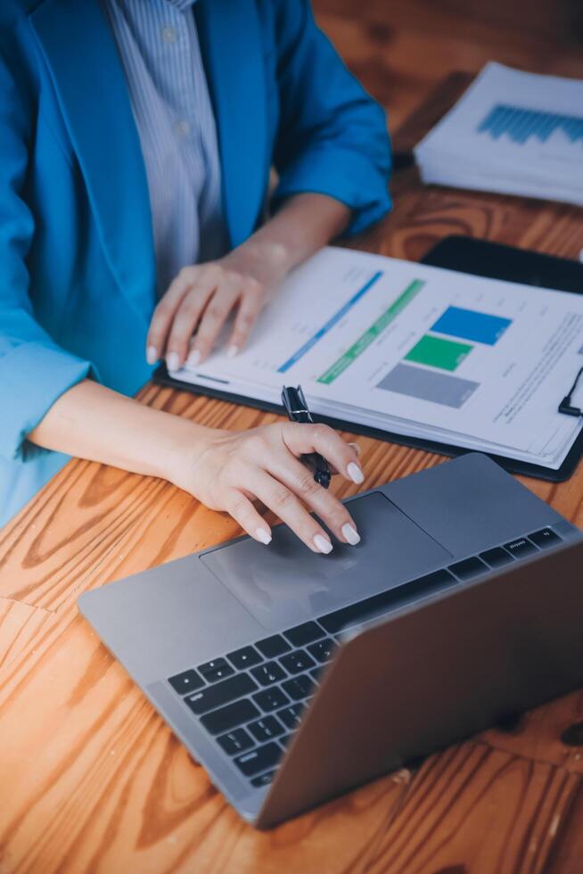 Asian Business woman using calculator and laptop for doing math finance on an office desk, tax, report, accounting, statistics, and analytical research concept photo