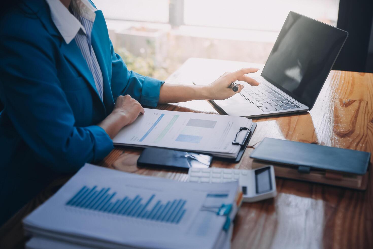 Asian Business woman using calculator and laptop for doing math finance on an office desk, tax, report, accounting, statistics, and analytical research concept photo