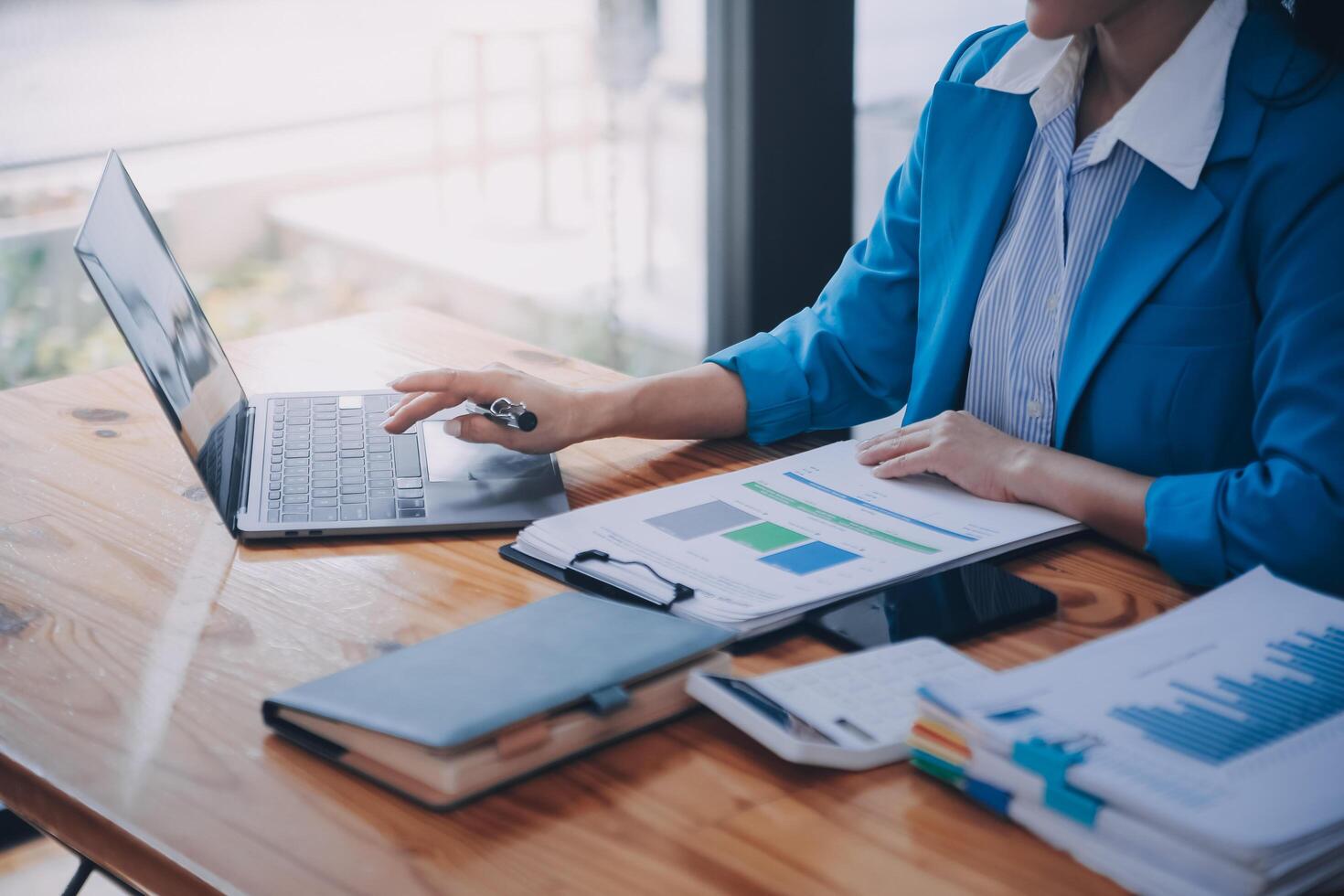 Asian Business woman using calculator and laptop for doing math finance on an office desk, tax, report, accounting, statistics, and analytical research concept photo